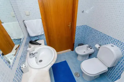 a blue tiled bathroom with a toilet and a sink at Ver o Mar in Albufeira