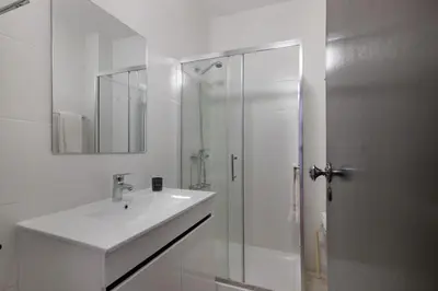 a white bathroom with a sink and a shower at Casa Mar Sol E Sossego in Albufeira