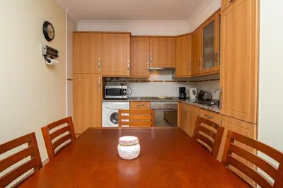 a kitchen with wooden cabinets and a wooden table with chairs at Central 2 Beedroms Old Tow Apartment in Albufeira