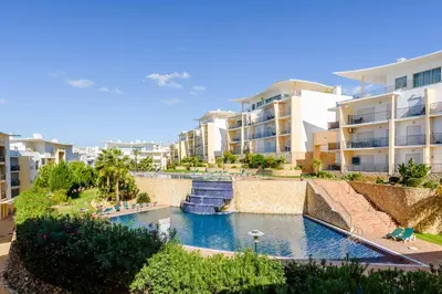a swimming pool in a resort with palm trees and buildings at BnB Homes Eco Apartment with Terrace, 2 Swimming pools & Tennis court in Albufeira