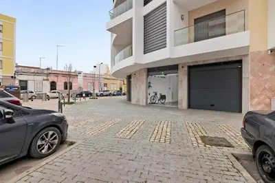 a parking lot with two cars parked in front of a building at São Luís Faro Apartment - Algarve in Faro