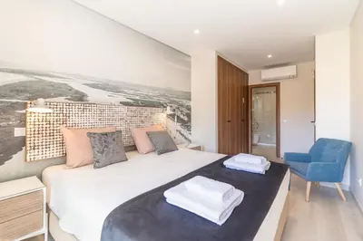 a bedroom with a large white bed and a blue chair at São Luís Faro Apartment - Algarve in Faro