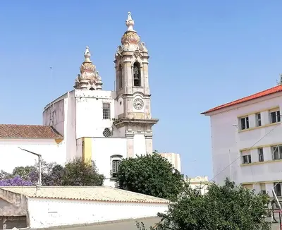 a white building with a clock tower on top of it at Casa do Pino in Faro