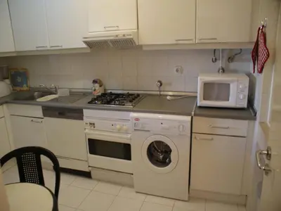 a kitchen with a washing machine and a microwave at Akisol Vilamoura Rise in Quarteira