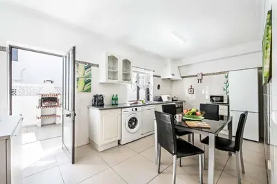 a white kitchen with a table and chairs and a sink at Villa Lela in Galé
