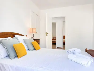 a bedroom with a white bed with yellow and blue pillows at Villa Brasil by BeCherish in Quarteira