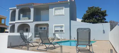 two chairs in front of a house with a swimming pool at Almancil Residence in Almancil