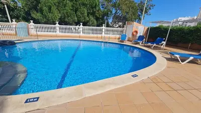 a large swimming pool with blue chairs and a fence at Sunbeam Home - Albufeira in Albufeira
