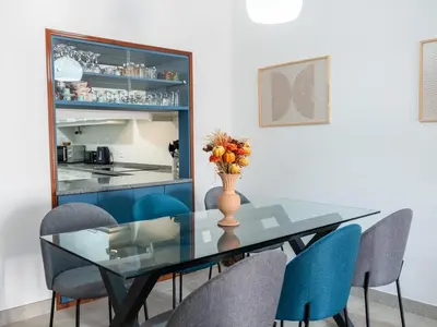 a dining room with a glass table and blue chairs at Balaia Praia Apartment by Stay ici Algarve Holiday Rental in Albufeira