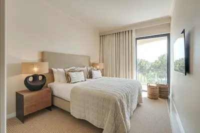 a bedroom with a bed and a large window at Apartamento T2 renovado no Vila Sol com piscina in Vilamoura