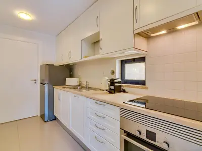 a kitchen with white cabinets and a sink at Apartamento T2 renovado no Vila Sol com piscina in Vilamoura