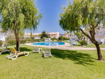 a yard with chairs and a swimming pool at Apartamento JV com 2 quartos e piscina, Vilamoura in Quarteira
