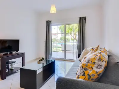 a living room with a couch and a glass table at Apartamento JV com 2 quartos e piscina, Vilamoura in Quarteira