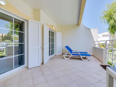a balcony with a table and chairs and trees at Apartamento JV com 2 quartos e piscina, Vilamoura in Quarteira