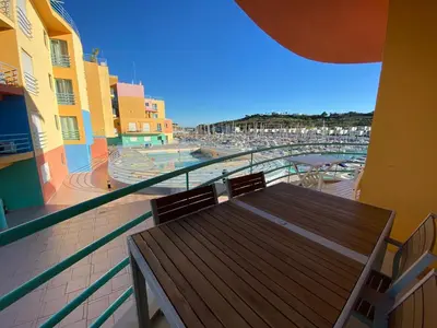 a balcony with a wooden bench and a view of a beach at Marina Pool & Sea in Albufeira