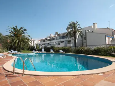 a large swimming pool with palm trees and a building at Premium Apartment with Vilamoura Marina View in Vilamoura