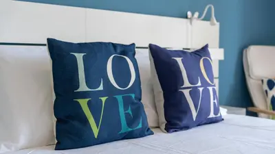 a bed with two blue pillows with the word love at Cozy 1Bdr Flat w Pool in Vilamoura by Lovelystay in Quarteira