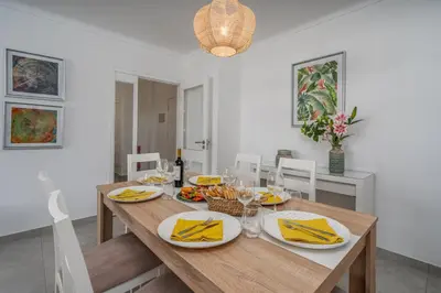 a dining room with a wooden table with food on it at Vilamoura Retreat with Pool & Balcony by HostWise in Quarteira