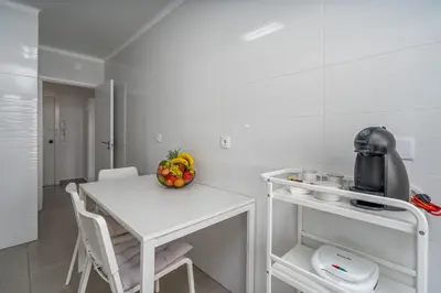 a white kitchen with a table and a bowl of fruit at Vilamoura Retreat with Pool & Balcony by HostWise in Quarteira