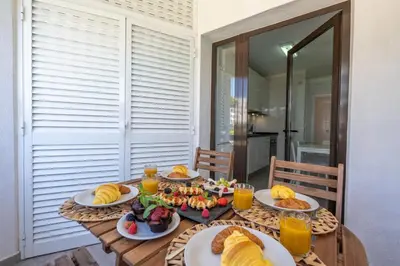 a wooden table with plates of food on it at Vilamoura Retreat with Pool & Balcony by HostWise in Quarteira