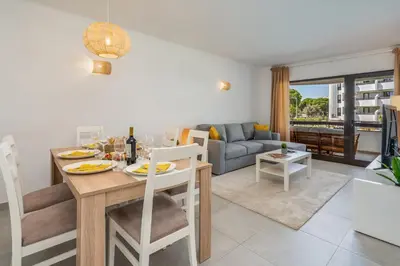 a kitchen and living room with a table and chairs at Vilamoura Retreat with Pool & Balcony by HostWise in Quarteira