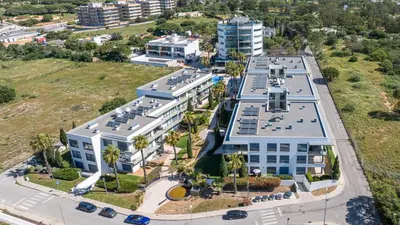 an overhead view of a white building with palm trees at Cavalo Preto Ocean Breeze Apartment in Forte Novo Quarteira in Quarteira