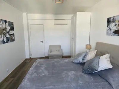 a bedroom with a large bed and a chair at CityComfort in Faro
