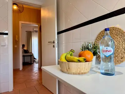 a bowl of bananas and oranges on a counter with a bottle at Cosy 1-Bedroom Apartment with Private Terrace in Loulé in Loulé