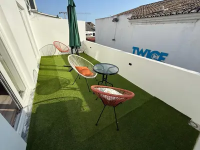 three chairs and a table on a balcony with green grass at Camilas Place 2 in Bicas