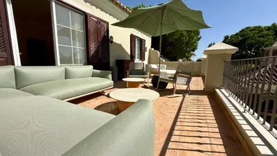 a patio with a couch and a table and an umbrella at Belinha - PINHEIROS ALTOS in Ludo