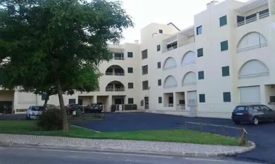 a large white building with cars parked in a parking lot at Salgados Village, Santos Apartment in Guia
