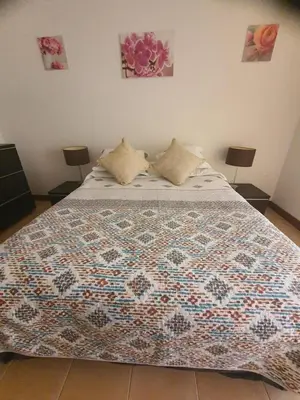 a bed with a quilt on it in a bedroom at Salgados Village, Santos Apartment in Guia