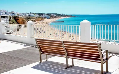 a bench sitting on a balcony overlooking a beach at 150m to the beach at Sol a Sul apartments in Albufeira