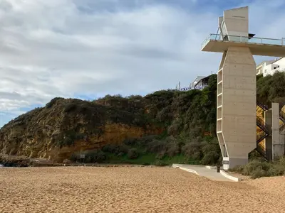 a building on a beach next to a mountain at 150m to the beach at Sol a Sul apartments in Albufeira