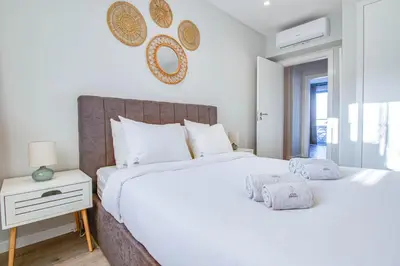 a white bedroom with a large bed and a nightstand at Stunning Ocean View Apt Beach 200mt AC Pool in Albufeira