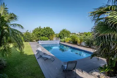 a swimming pool with two chairs on a wooden deck at Luxury home in Albufeira in Albufeira