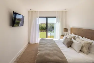 a bedroom with a large bed with a television on the wall at Faro Luxury Home with Heated Pool and Garden in Faro