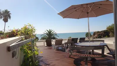 a wooden deck with a table and an umbrella at Fantastic Apartment On The Beach in Albufeira