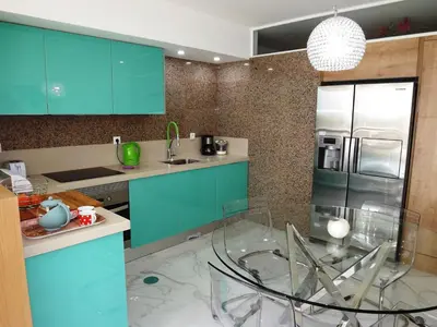 a kitchen with blue cabinets and a glass chair in it at Fantastic Apartment On The Beach in Albufeira