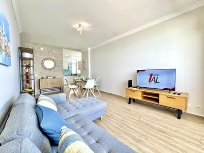 a living room with a blue couch and a flat screen tv at Quarteira Central Beach 5 by Homing in Quarteira