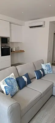 a living room with a gray couch with blue pillows at Skynest 61 Faro Airport Guest House in Faro