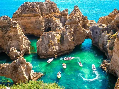 a body of water with rocks in the water at Ocean Breeze Rooms, Albufeira in Albufeira