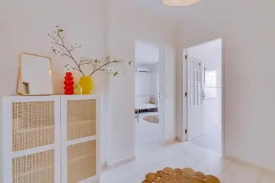 a white hallway with a mirror and a table at Brisa Algarvia 1 in Faro