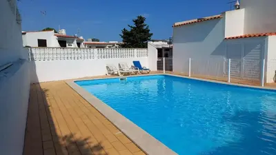 a swimming pool with two chairs next to a building at Villa UM in Albufeira