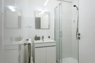 a white bathroom with a sink and a shower at Mare Viva - Seafront with pool by HD in Quarteira