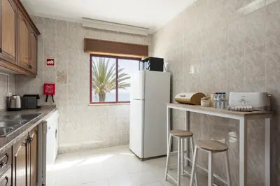 a kitchen with a refrigerator and two bar stools at Mare Viva - Seafront with pool by HD in Quarteira