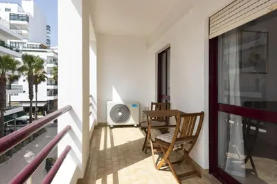 a balcony with a chair and a fan at Mare Viva - Seafront with pool by HD in Quarteira