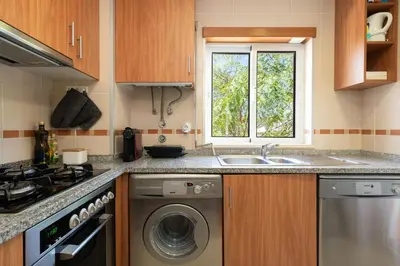 a kitchen with a sink and a washing machine at 1 Bedroom apt with pool access in Albufeira