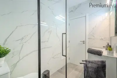 a bathroom with a shower with marble walls at Peneco Beach Apartment Old Town in Albufeira