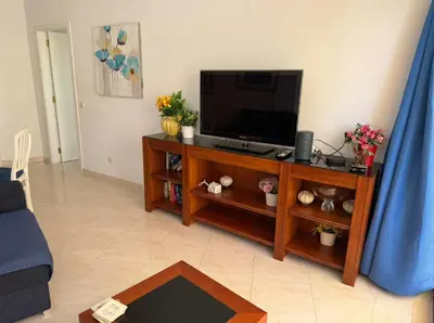 a living room with a flat screen tv on a entertainment center at Modern 2BR Vilamoura Stay Pool Access Golf Nearby 15 Percent Off in Quarteira